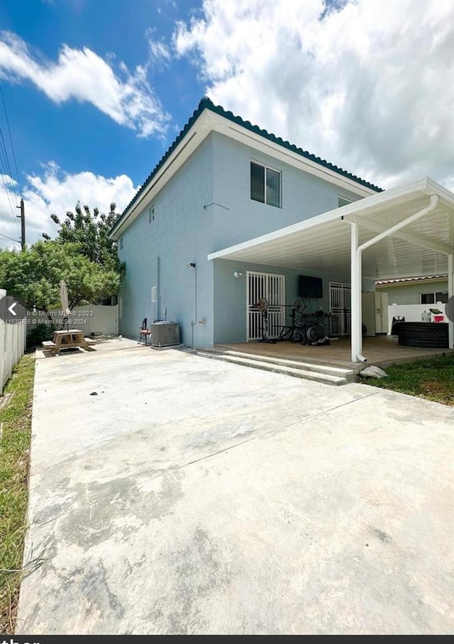 rear view of property featuring central AC unit and a patio area