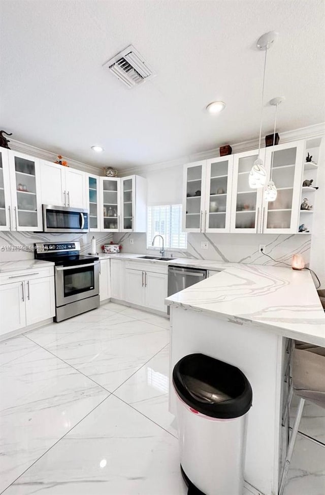 kitchen with white cabinetry, appliances with stainless steel finishes, kitchen peninsula, pendant lighting, and light stone countertops