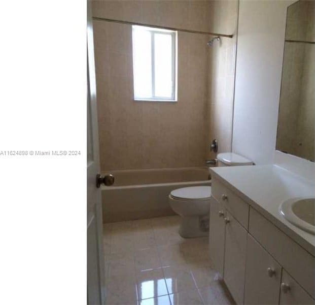 full bathroom with tiled shower / bath combo, vanity, tile patterned flooring, and toilet