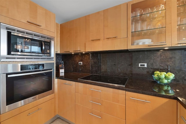 kitchen featuring appliances with stainless steel finishes, backsplash, and dark stone countertops