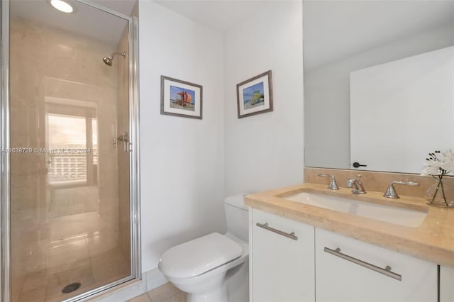 bathroom featuring tile patterned flooring, vanity, toilet, and a shower with shower door