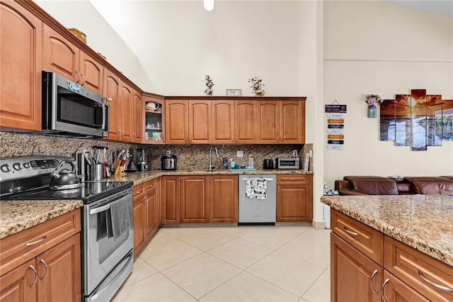 kitchen with decorative backsplash, light tile patterned floors, stainless steel appliances, and light stone counters