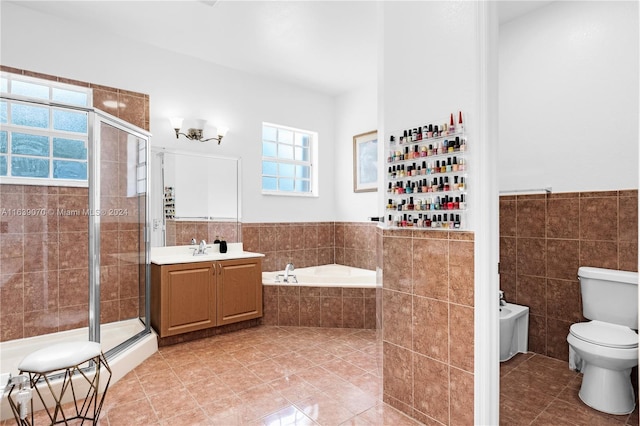 full bathroom with tile walls, vanity, tile patterned flooring, independent shower and bath, and a bidet