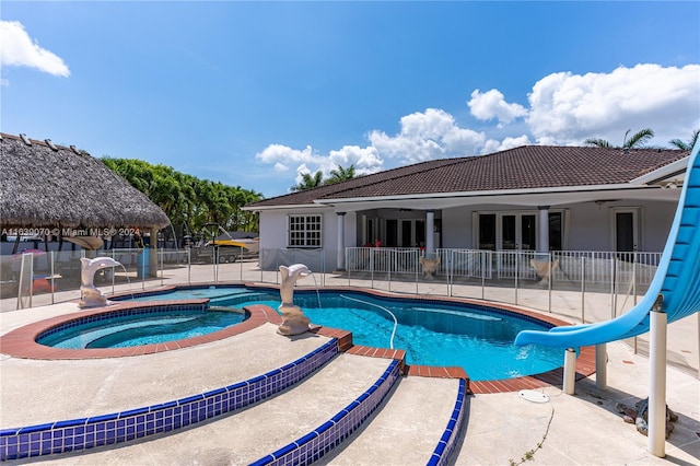 view of pool featuring a water slide, an in ground hot tub, and a patio area