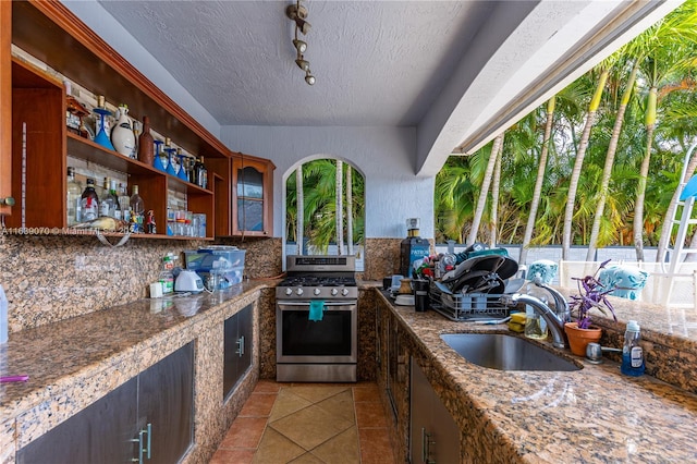 kitchen with a textured ceiling, a healthy amount of sunlight, range, backsplash, and sink