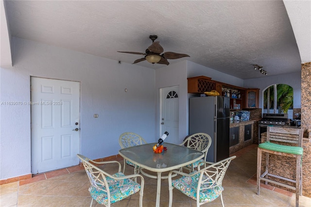 tiled dining space featuring ceiling fan and a textured ceiling