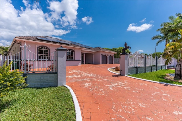 mediterranean / spanish-style home featuring a front lawn and solar panels