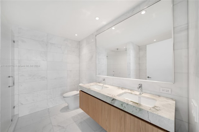 full bathroom featuring toilet, a shower stall, tile walls, and a sink