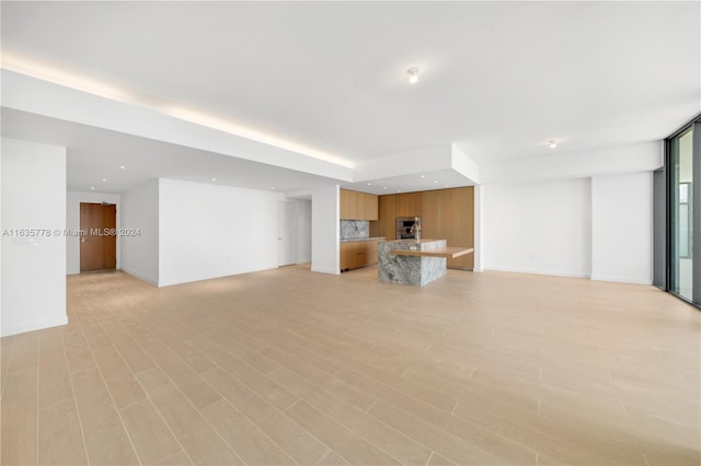 unfurnished living room featuring baseboards, recessed lighting, and light wood-style floors