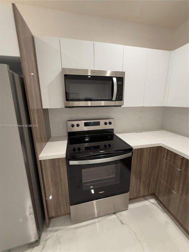 kitchen featuring white cabinets, stainless steel appliances, and dark brown cabinets