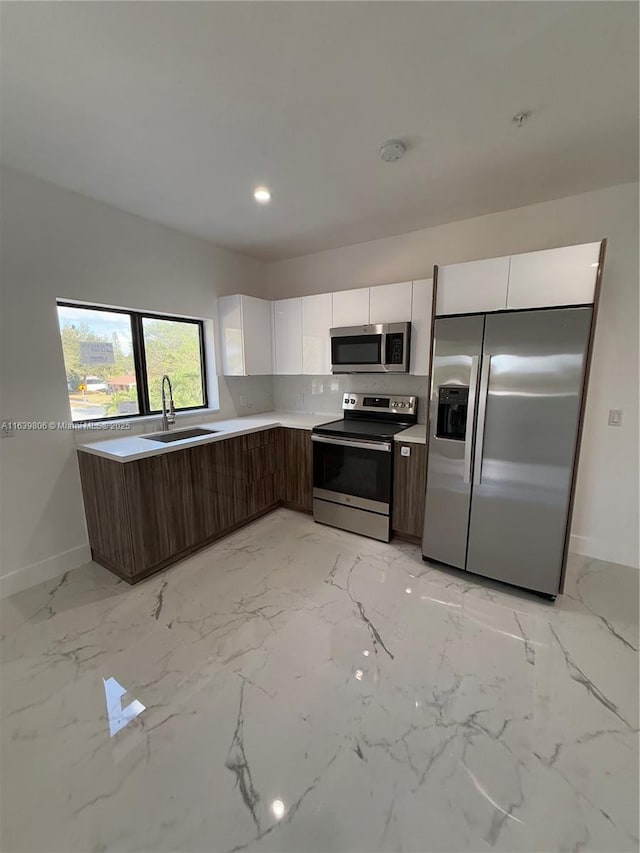 kitchen featuring dark brown cabinets, sink, white cabinets, decorative backsplash, and stainless steel appliances