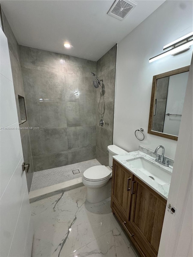 bathroom with tiled shower, toilet, and vanity