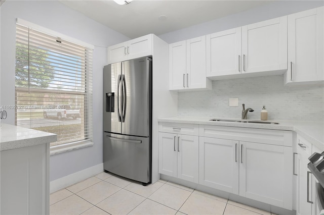 kitchen with stainless steel fridge with ice dispenser, light tile patterned floors, sink, and white cabinetry