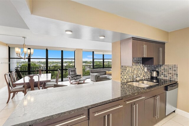 kitchen featuring sink, light tile patterned floors, dark stone countertops, a notable chandelier, and stainless steel dishwasher