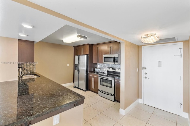 kitchen with backsplash, stainless steel appliances, sink, and light tile patterned flooring