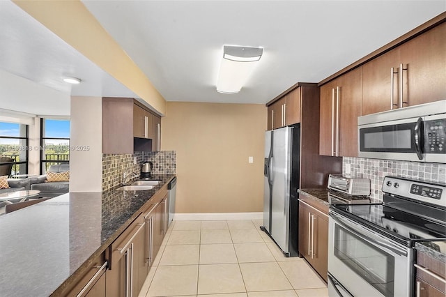 kitchen with light tile patterned flooring, sink, dark stone counters, decorative backsplash, and stainless steel appliances