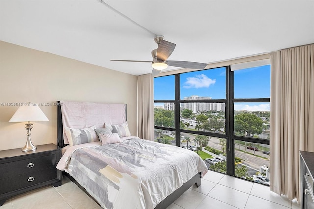 bedroom featuring ceiling fan, a wall of windows, and light tile patterned floors