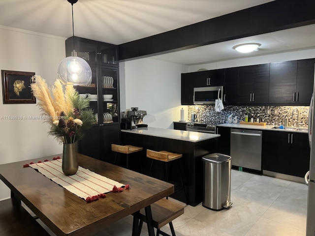 kitchen with pendant lighting, appliances with stainless steel finishes, sink, light tile patterned floors, and decorative backsplash