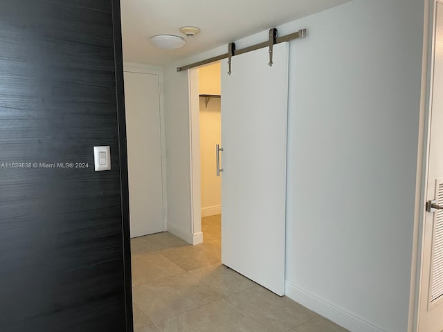 hall featuring light tile patterned floors and a barn door