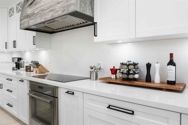 kitchen with custom exhaust hood, black electric stovetop, white cabinets, and oven