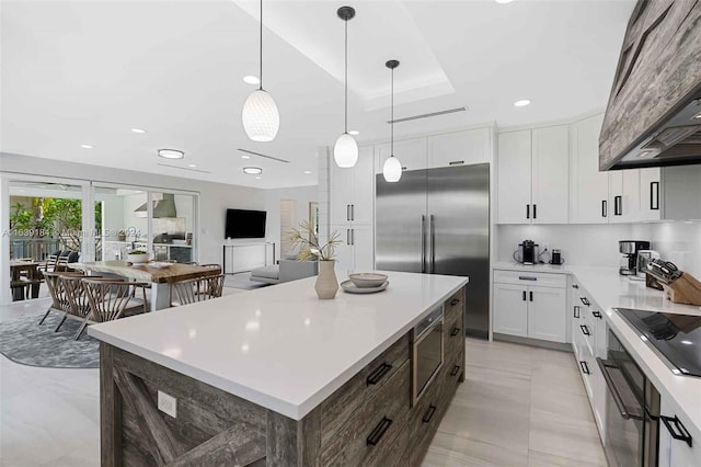 kitchen with built in appliances, white cabinets, light tile patterned floors, a center island, and premium range hood