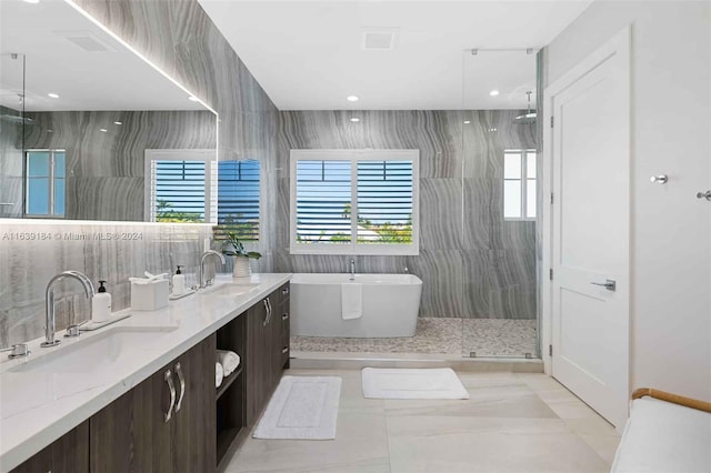 bathroom featuring double sink vanity, tile walls, plus walk in shower, and tile patterned flooring