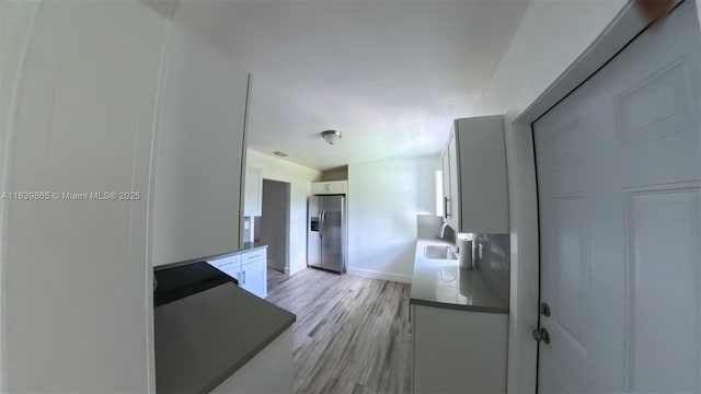 kitchen with light hardwood / wood-style floors, sink, white cabinetry, and stainless steel refrigerator with ice dispenser