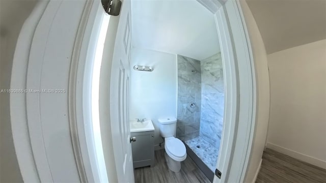 bathroom featuring tiled shower, hardwood / wood-style floors, vanity, and toilet