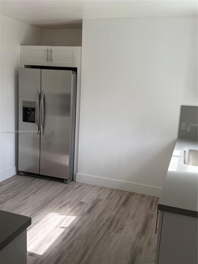 kitchen featuring stainless steel fridge with ice dispenser, light hardwood / wood-style flooring, and white cabinets