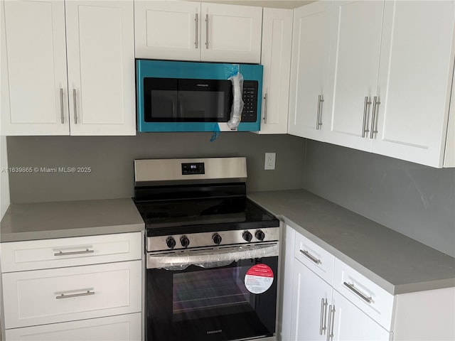 kitchen with backsplash, white cabinets, and appliances with stainless steel finishes