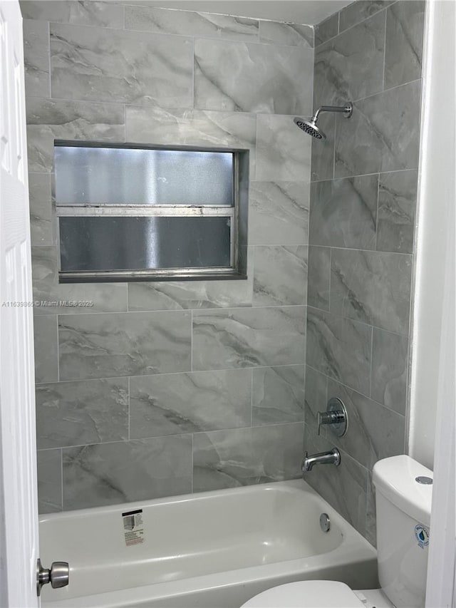 bathroom with tiled shower / bath combo and toilet