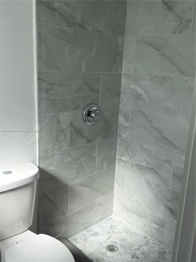 bathroom with toilet and tiled shower