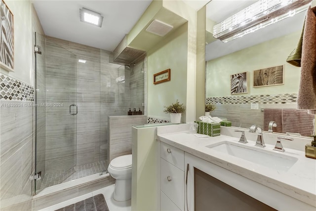 bathroom featuring vanity, tile walls, visible vents, toilet, and a shower stall