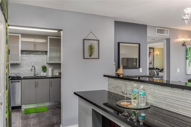 bar featuring stainless steel dishwasher, visible vents, a sink, and decorative backsplash