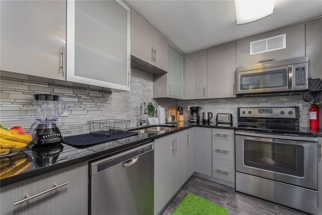 kitchen featuring stainless steel appliances, gray cabinetry, tasteful backsplash, and a sink