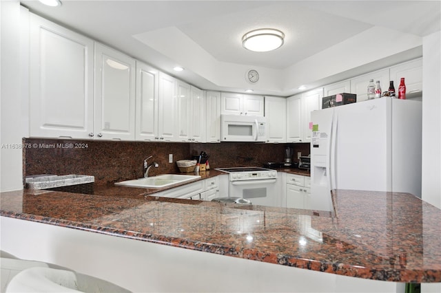 kitchen with kitchen peninsula, sink, white cabinets, and white appliances