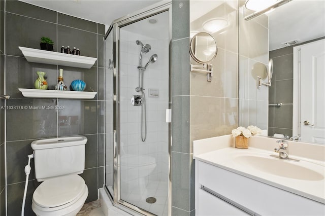 bathroom featuring vanity, toilet, tile walls, and a shower with shower door