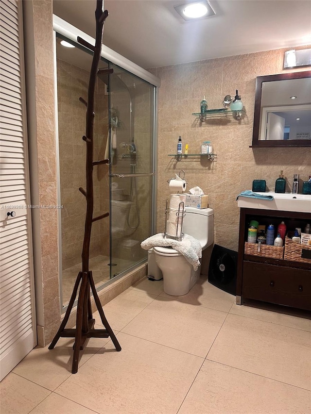 bathroom featuring toilet, vanity, a shower with shower door, and tile patterned flooring