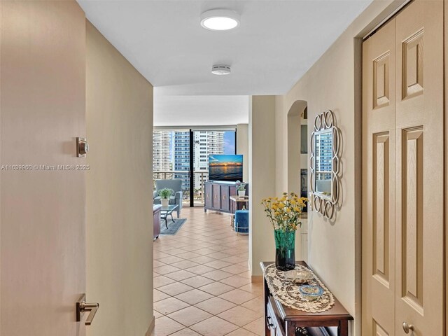 corridor with floor to ceiling windows and light tile patterned floors