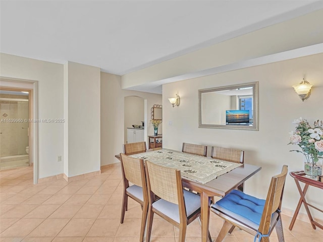 dining space with light tile patterned flooring and arched walkways