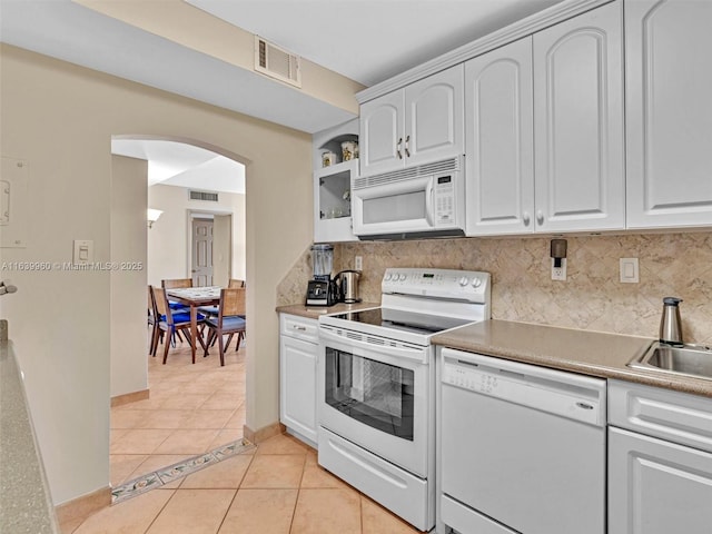 kitchen featuring visible vents, backsplash, white appliances, arched walkways, and light tile patterned flooring