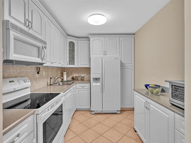 kitchen featuring white appliances, sink, light tile patterned floors, and white cabinets