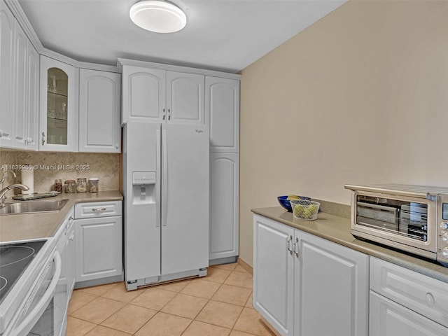 kitchen featuring white cabinetry, light tile patterned flooring, white fridge with ice dispenser, and a sink