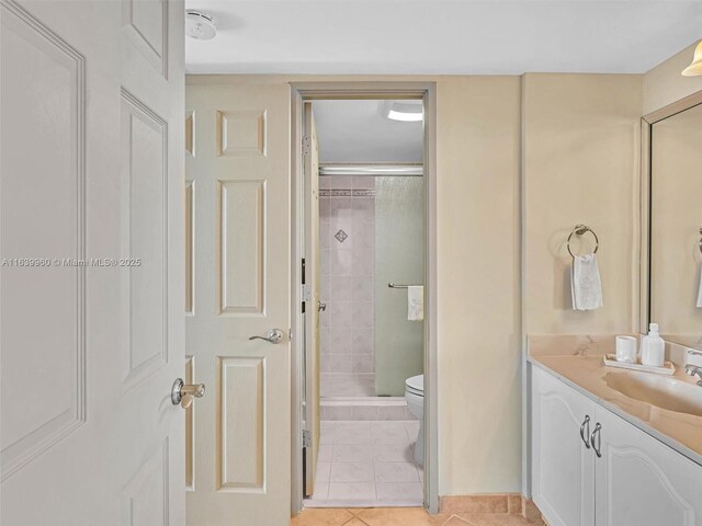 bathroom featuring tile patterned flooring, vanity, toilet, and walk in shower