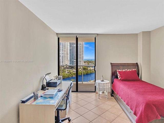 bedroom featuring light tile patterned floors, a wall of windows, access to exterior, and a water view