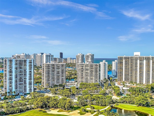 drone / aerial view featuring a city view, golf course view, and a water view