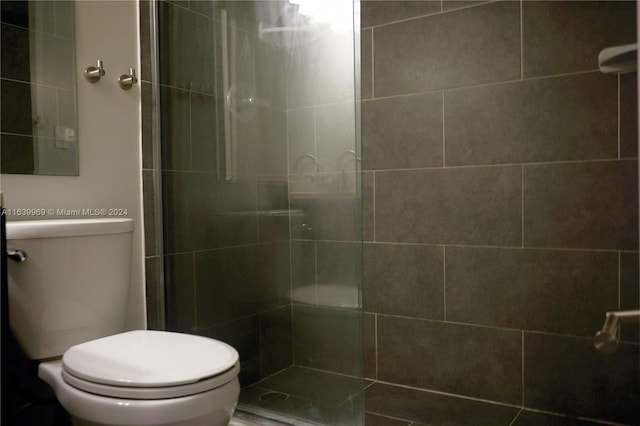 bathroom with a shower with door and toilet