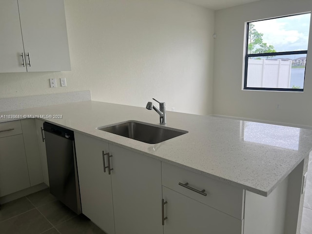 kitchen with stainless steel dishwasher, tile patterned flooring, light stone countertops, sink, and kitchen peninsula