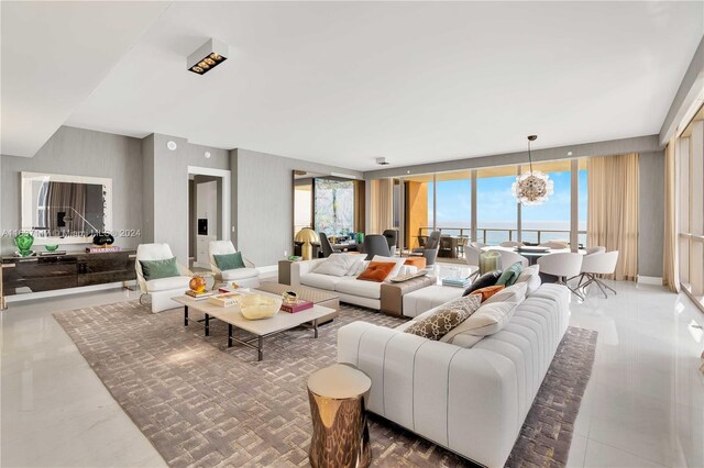 living room with a notable chandelier, a water view, plenty of natural light, and a wall of windows