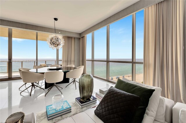 tiled dining area featuring a notable chandelier, a water view, and plenty of natural light